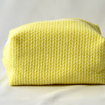 Back view of a bright yellow cosmetic pouch with a soft, quilted knit-pattern fabric. The bag features a structured, padded shape with a clean, minimalist design and no visible front label.