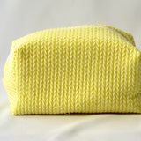 Back view of a bright yellow cosmetic pouch with a soft, quilted knit-pattern fabric. The bag features a structured, padded shape with a clean, minimalist design and no visible front label.