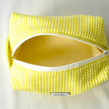 Open cosmetic pouch in bright yellow with a soft, quilted knit-pattern fabric and a white zipper. The bag reveals a spacious, light-colored interior, highlighting its practical design for everyday essentials.