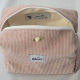 Open view of a blush pink cosmetic pouch made from soft corduroy fabric with a white zipper. The bag reveals a light-colored interior with a sewn-in label that reads “keep going, you can do this,” along with small heart details, combining functionality with an encouraging message.