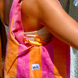 A person wearing a pink and orange striped towel shoulder bag with a yellow drawstring and a visible 'glow' brand label.